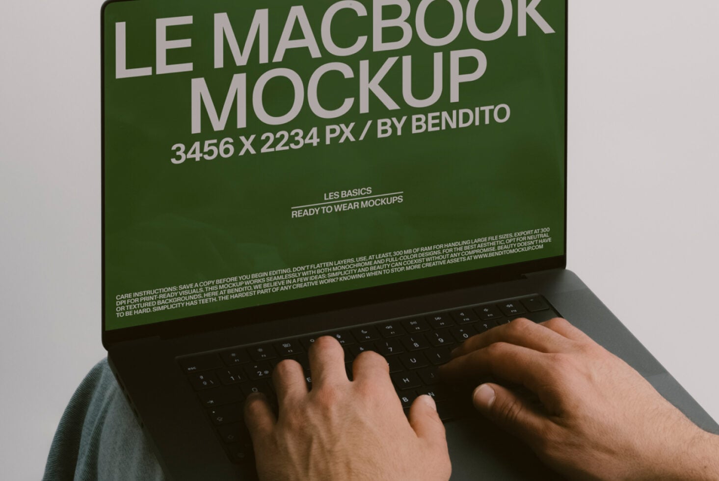 Hands typing on MacBook keyboard with green screen displaying mockup text