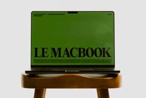 MacBook mockup on wood stool displaying bright green screen with large serif type