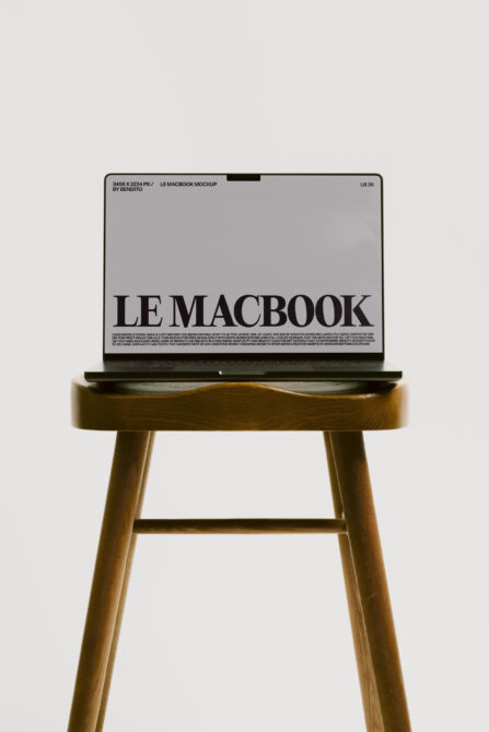 MacBook mockup on wood stool showing gray screen with black text layout