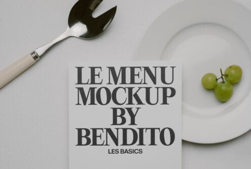 Black text menu mockup on cream card with fork, plate, grapes on white surface