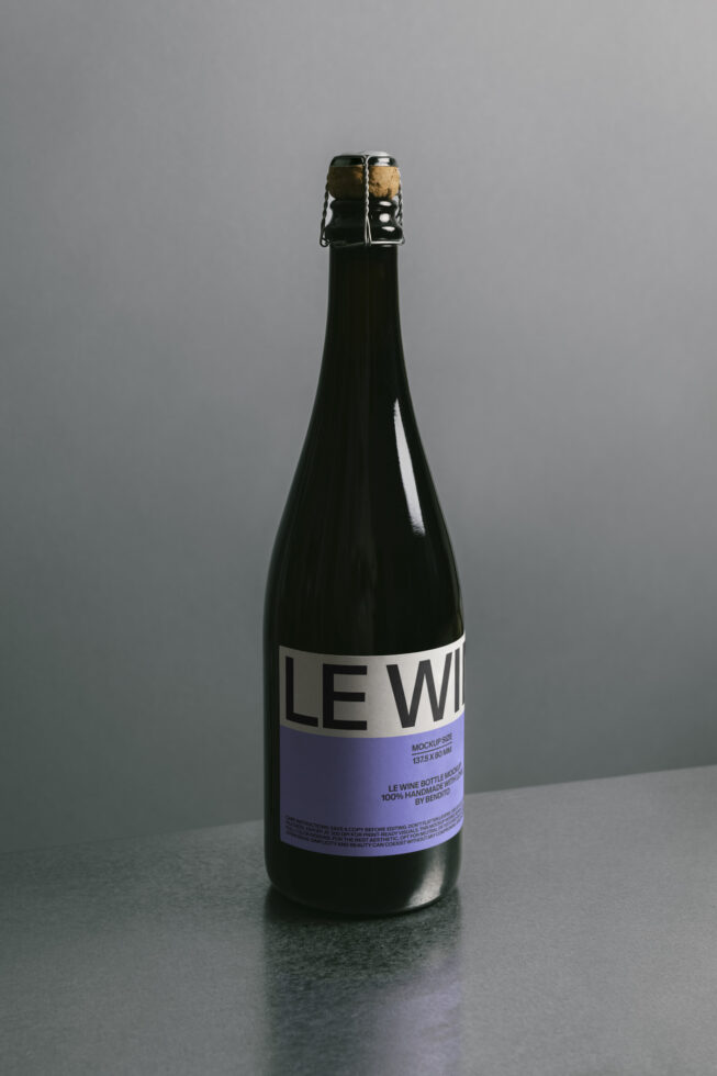 Dark glass bottle with white label mockup on gray surface