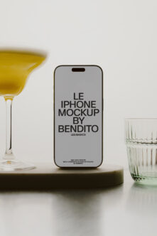 Gray iPhone mockup flanked by yellow cocktail on left, water glasses on right