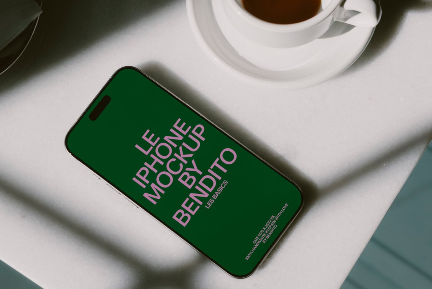 Green iPhone screen displaying Les Basics mockup text with coffee cup in background