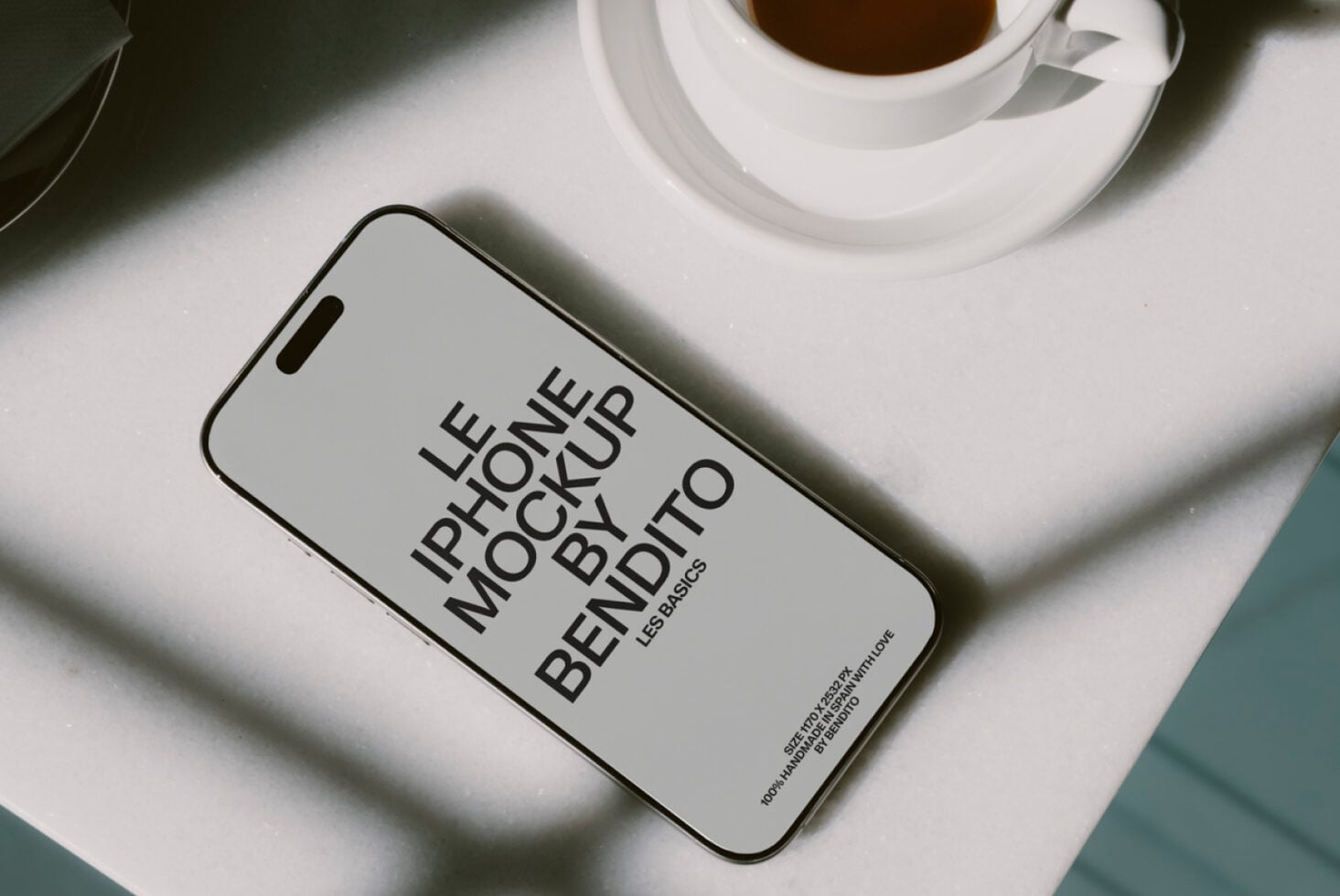 Light gray iPhone screen showing Les Basics mockup design with coffee cup nearby