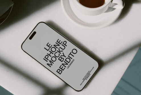 Light gray iPhone screen showing Les Basics mockup design with coffee cup nearby