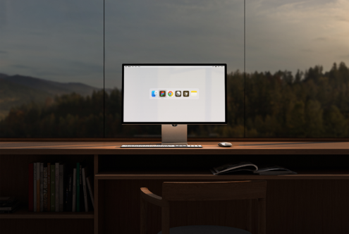 Modern desktop computer setup on wooden desk with keyboard and mouse, large window overlooking forest. Ideal for office mockup or workspace design