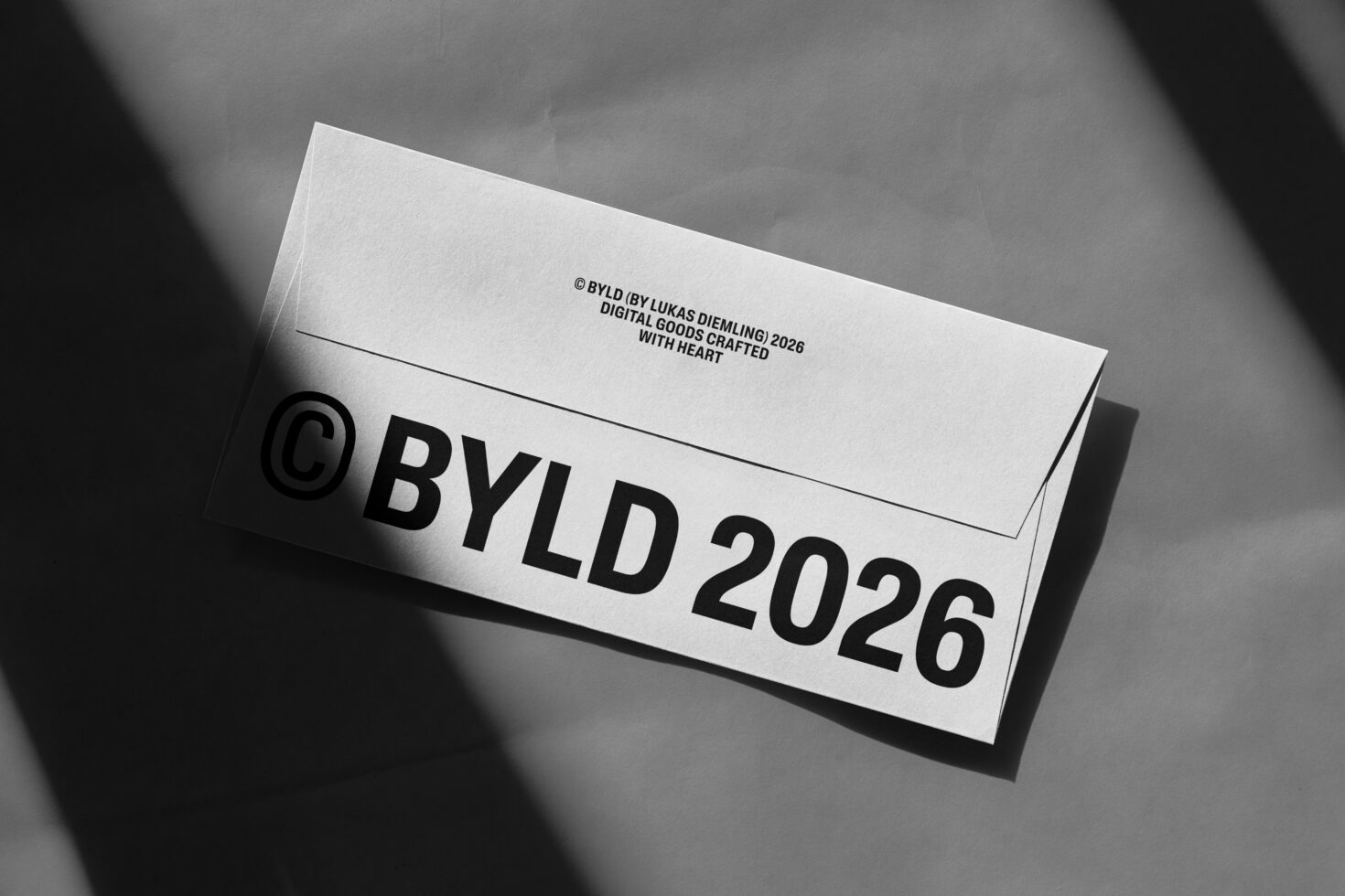 White envelope mockup with black text under dramatic light beam, overhead view