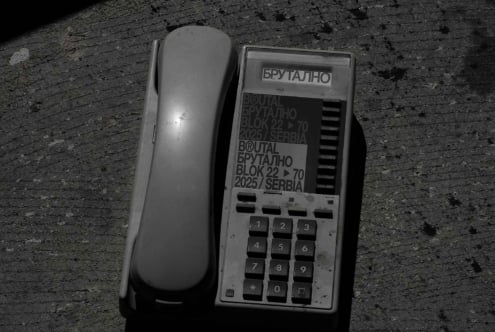 Vintage brutalist phone with keypad next to brutalist branding label on concrete