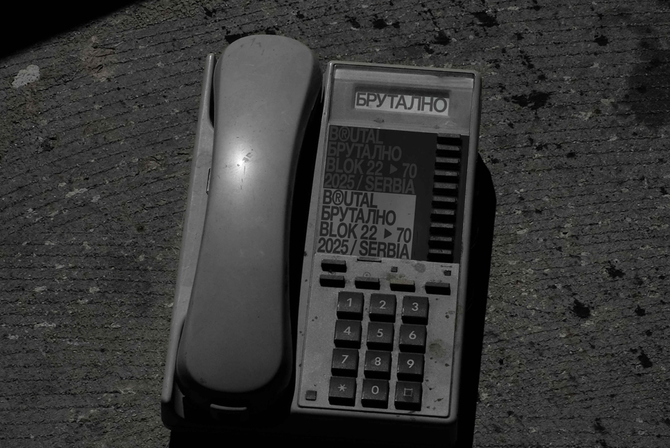 Vintage brutalist phone with keypad next to brutalist branding label on concrete