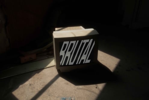 Brutal branded box mockup lit by sunlight in dark industrial space