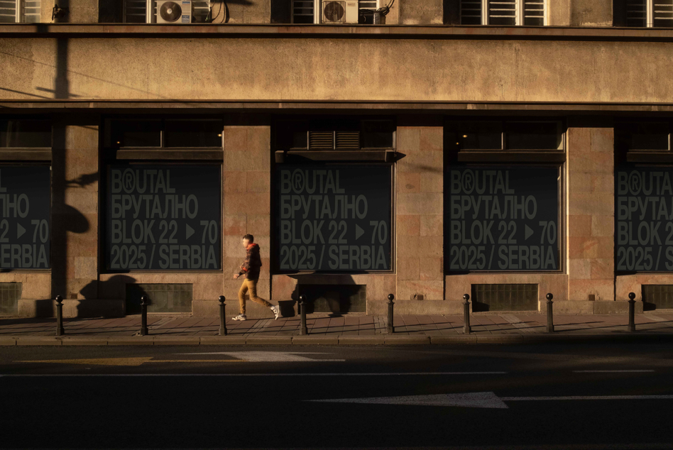 Window signage on tan stone building with person jogging brutal block mockup