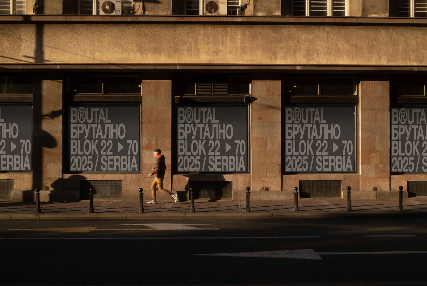 Street level window signage on tan stone building with runner brutal block text