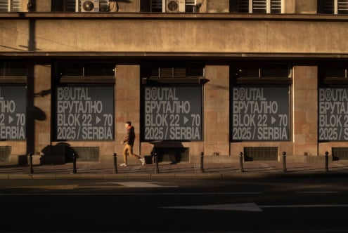 Street level window signage on tan stone building with runner brutal block text