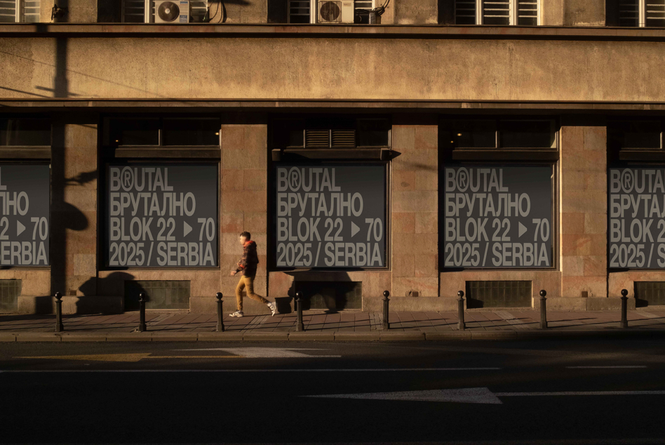 Street level window signage on tan stone building with runner brutal block text