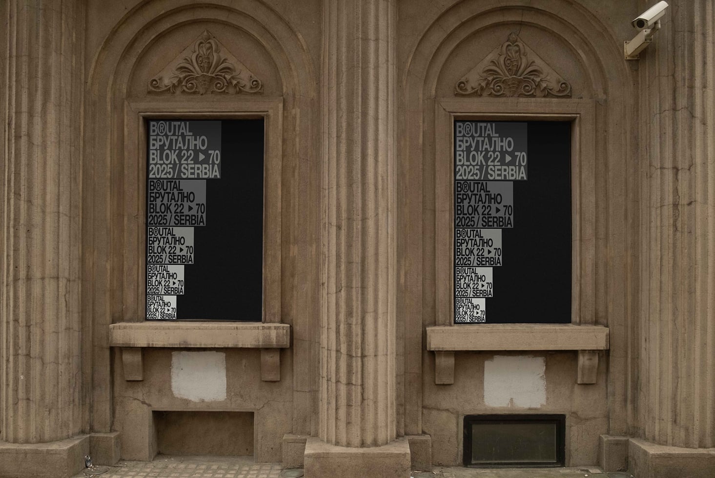Two ornate stone arches with black window signs showing repeated text patterns