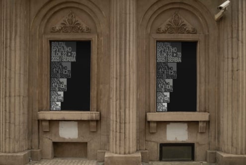 Two ornate stone arches with black window signs showing repeated text patterns