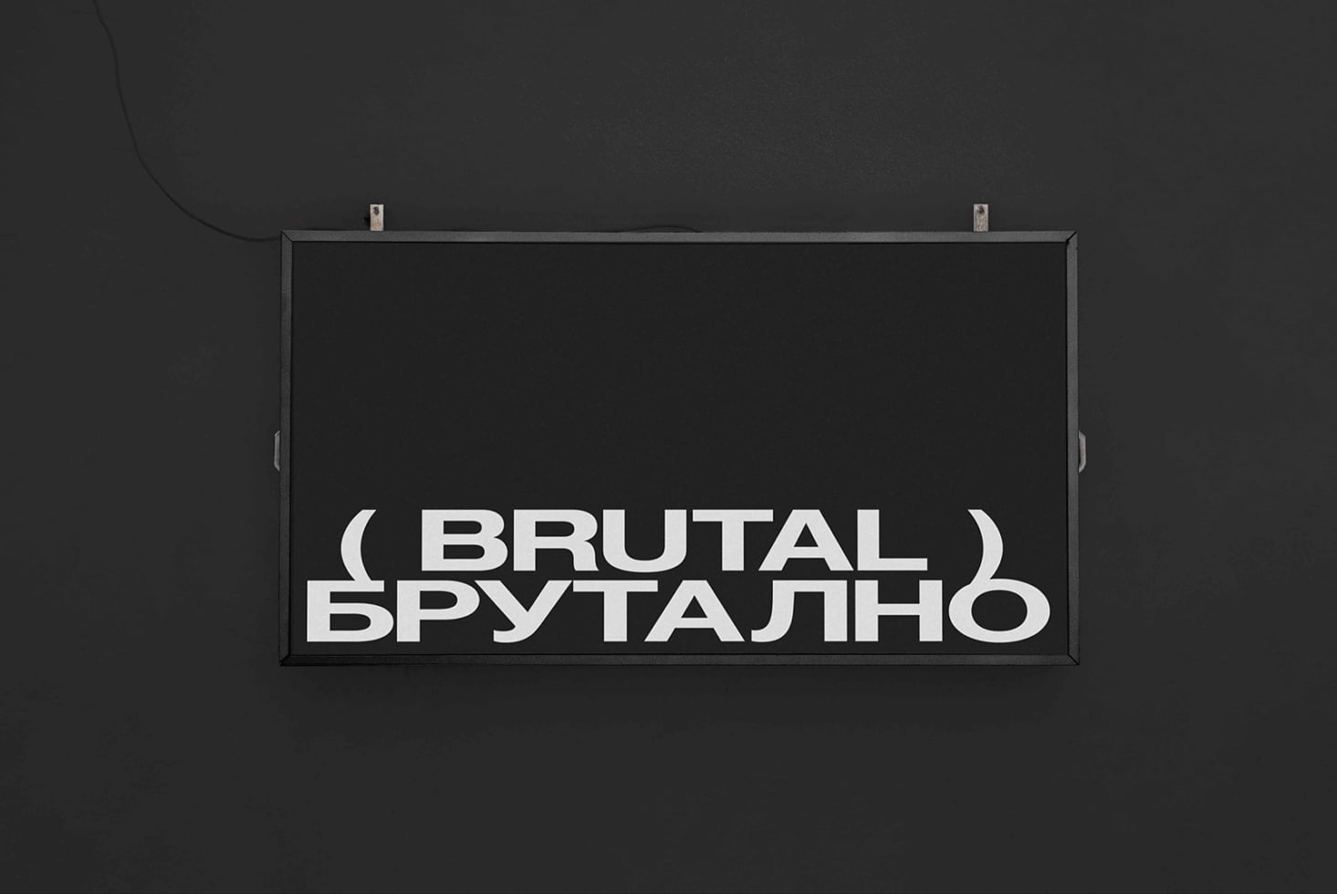 Dark horizontal sign on dark wall showing Brutal text in white sans serif letters