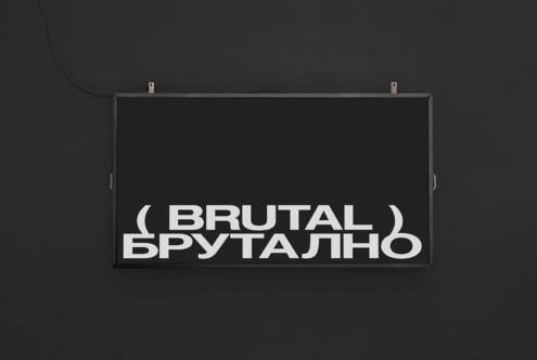 Dark horizontal sign on dark wall showing Brutal text in white sans serif letters