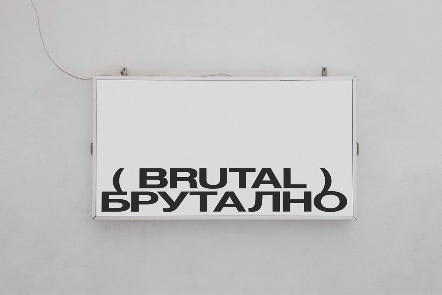 White horizontal sign mounted on wall displaying Brutal text in bold sans serif