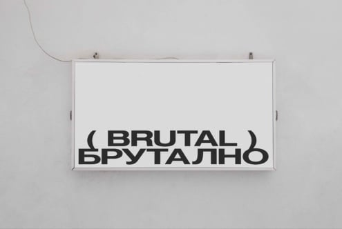 White horizontal sign mounted on wall displaying Brutal text in bold sans serif