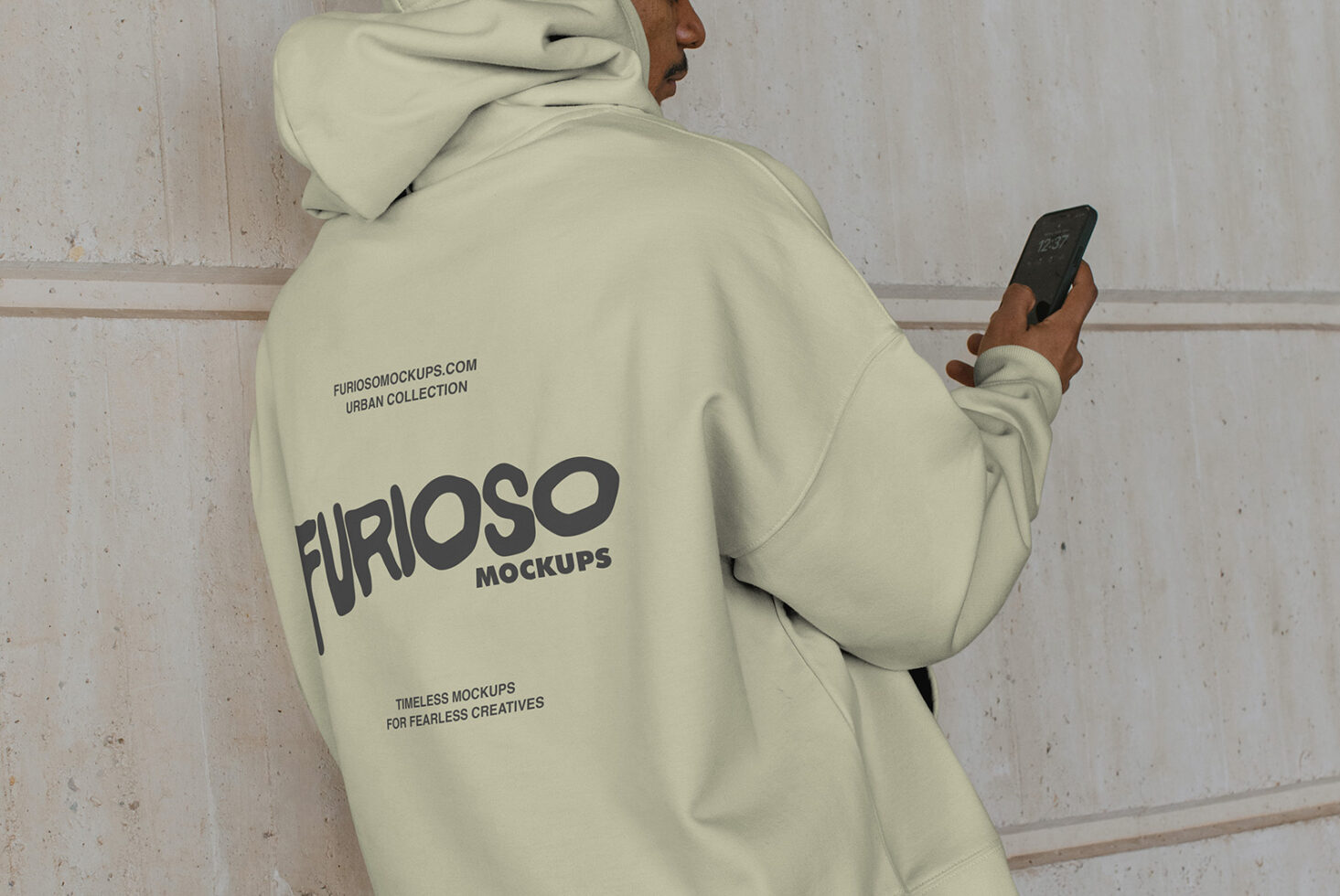 Cream hoodie side angle with person scrolling phone by wall