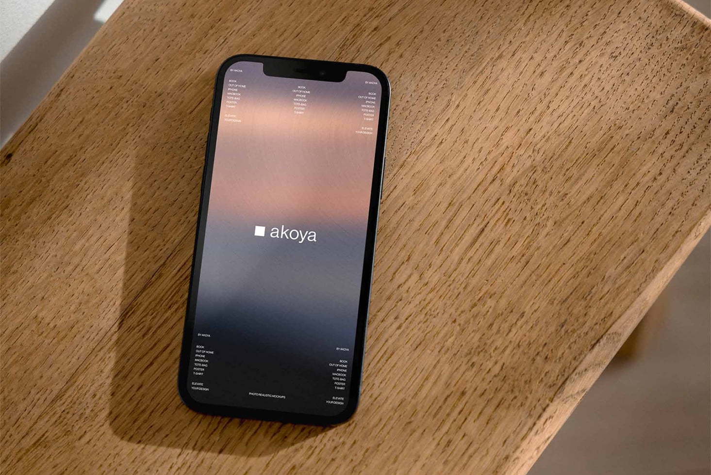 iPhone mockup on wooden surface displaying Akoya landing page with sunset gradient, minimal typography