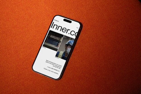 Black iPhone on orange background displaying Inner.co website design layout