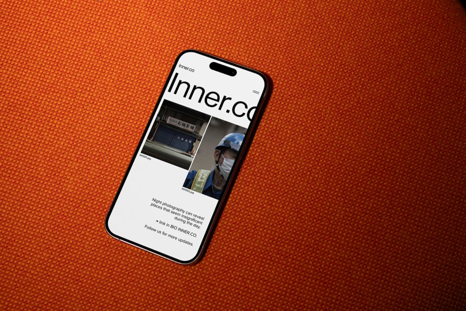 Black iPhone on orange background displaying Inner.co website design layout