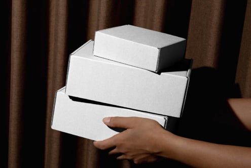 Four clean white boxes balanced in hands with fabric drape background