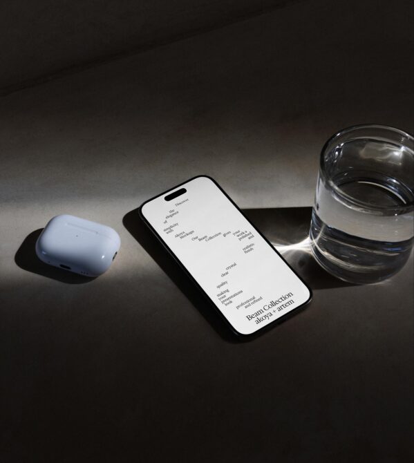 Smartphone mockup with white screen next to wireless earbuds plus water glass