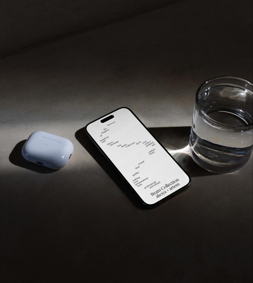Smartphone mockup with white screen next to wireless earbuds plus water glass