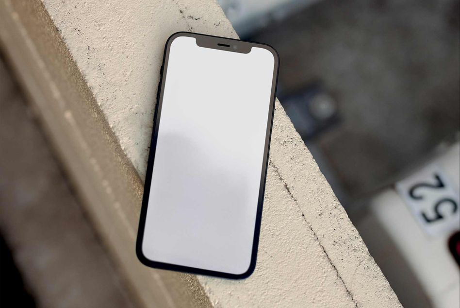 Black phone on concrete ledge with blank white screen