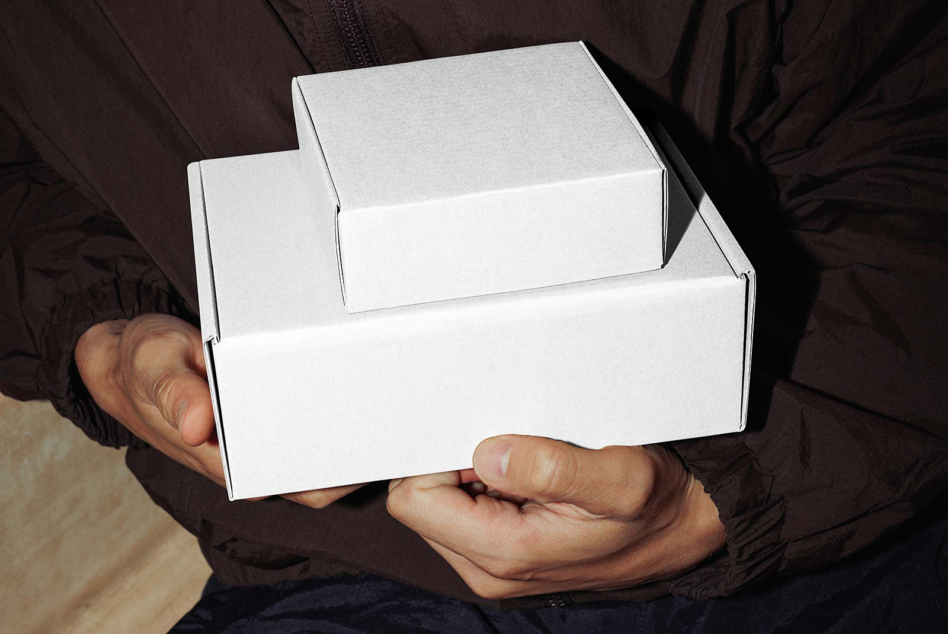 Hands displaying open white box with inner product packaging