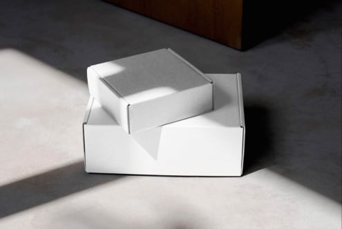 White open box with gray product box nestled inside, clean sunlit scene