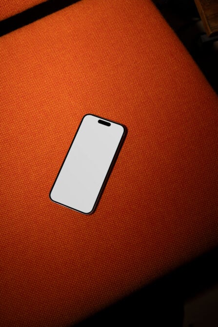 Smartphone mockup on orange fabric background, perfect for showcasing app designs, website layouts, or digital content in a modern, stylish setting.