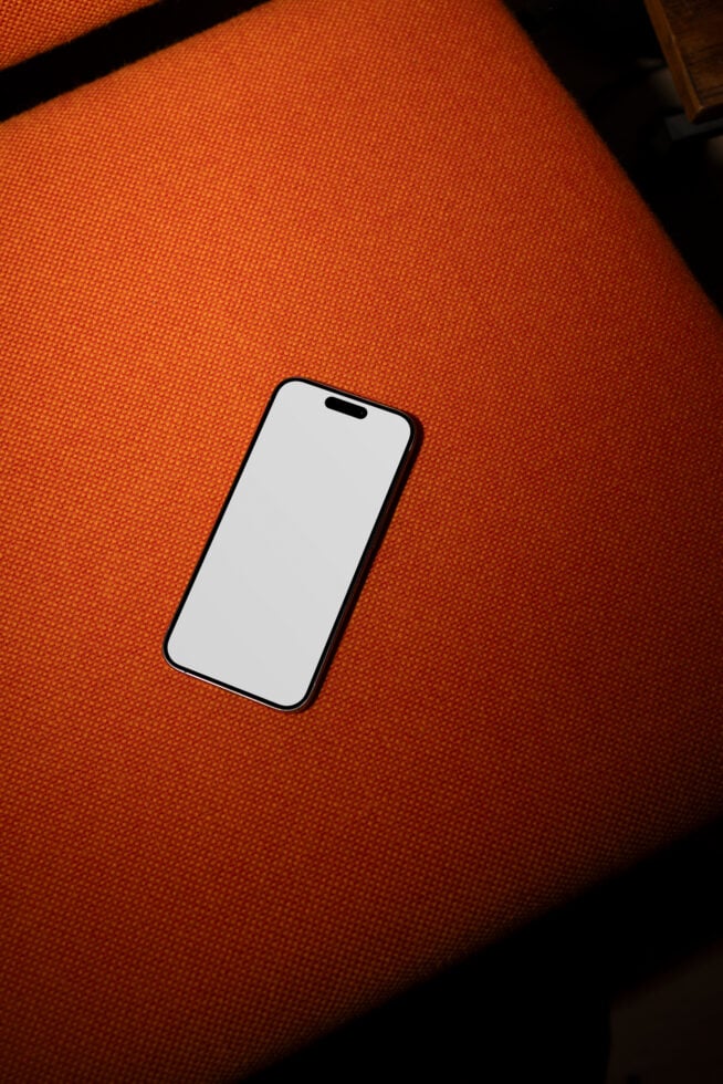 Smartphone mockup on orange fabric background, perfect for showcasing app designs, website layouts, or digital content in a modern, stylish setting.