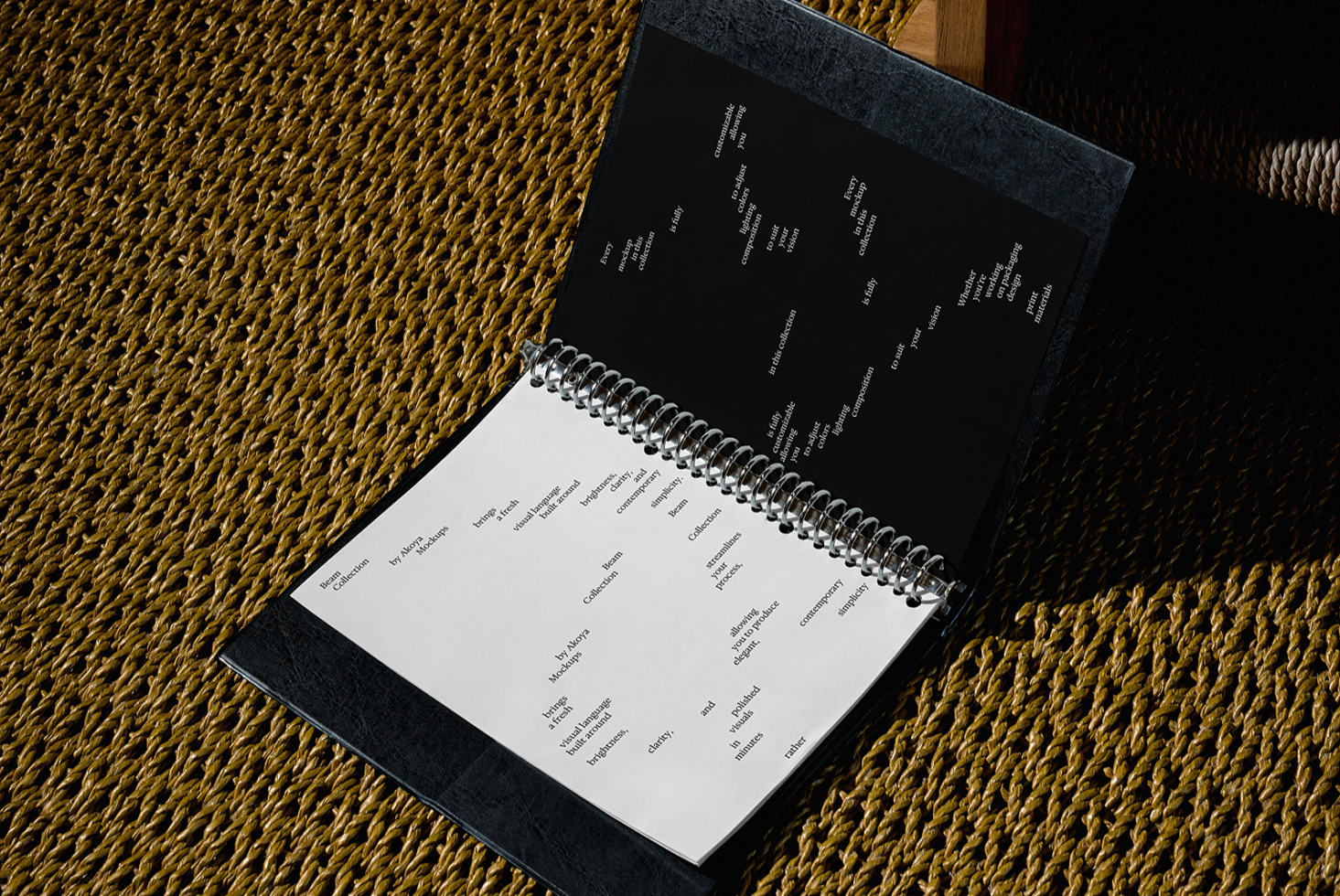 Spiral notebook with dark cover open on gold woven texture with wood frame