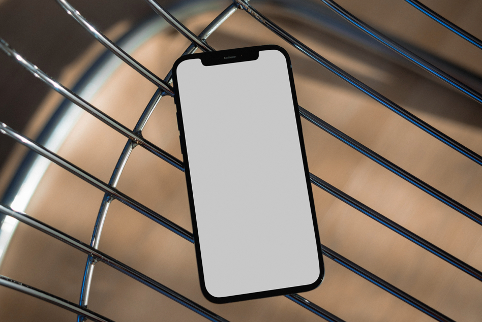 Blank white iPhone screen on striped metal background with diagonal shadow pattern