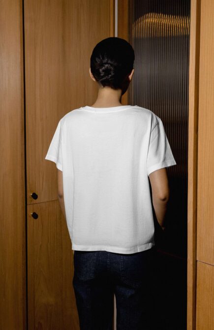 Back view of blank white tee between wood paneled doors