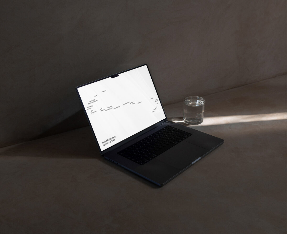 Black laptop with white screen showing Beam Collection text on concrete desk