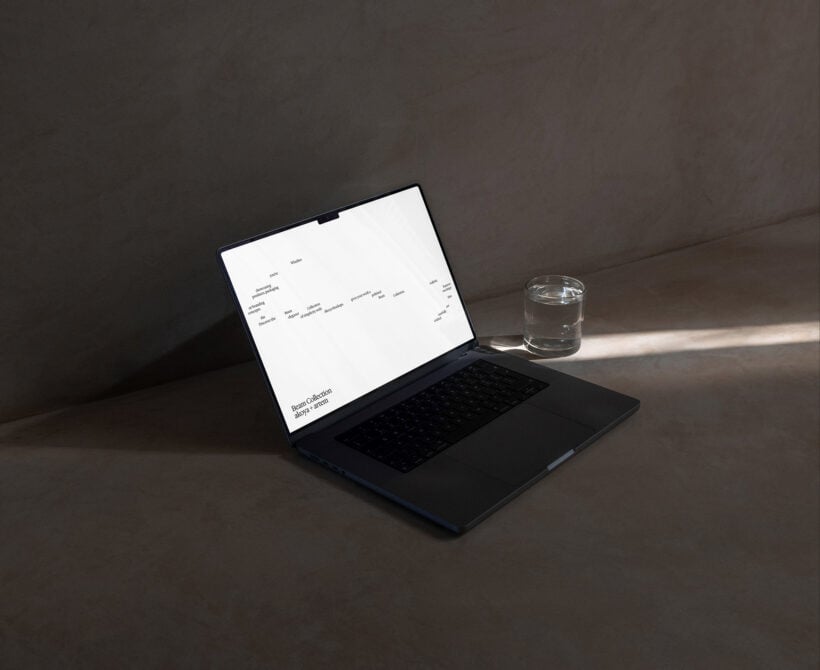 Black laptop with white screen showing Beam Collection text on concrete desk