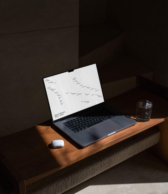 Laptop on wooden desk showing Beam Collection mockup on screen