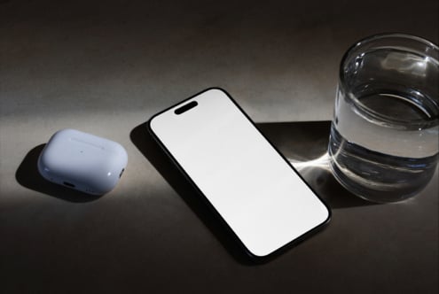 Smartphone mockup blank screen with wireless buds plus water glass on surface