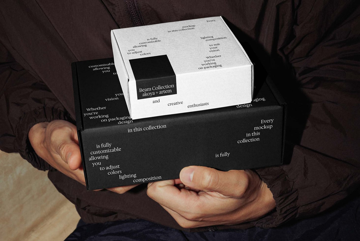 Hands holding stacked black white boxes with branded label insert