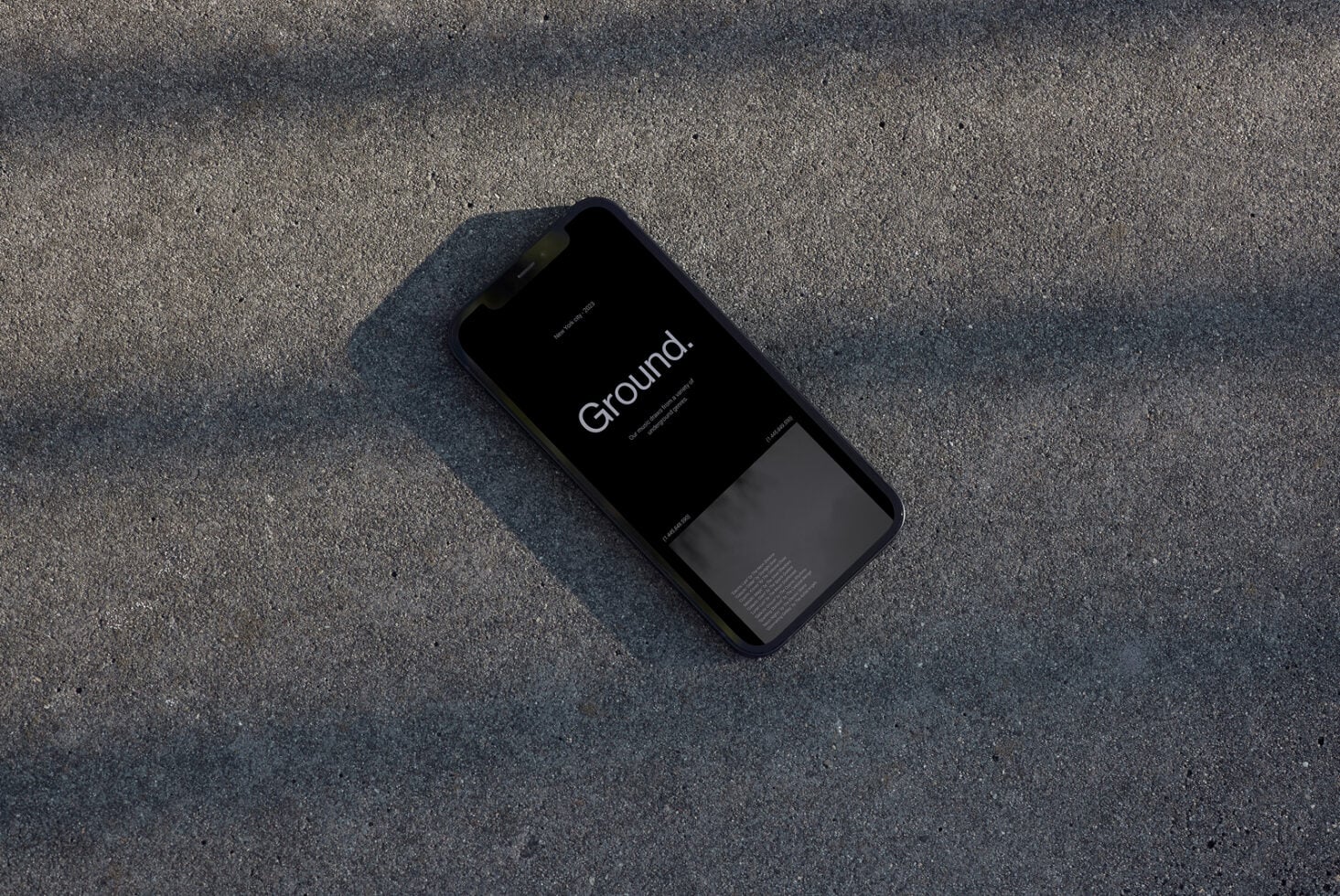 Black iPhone mockup displaying "Ground" app on concrete surface overhead shot