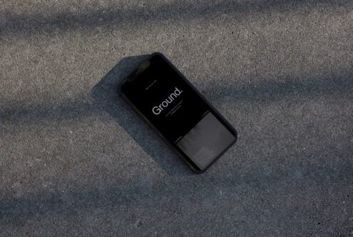 Black iPhone mockup displaying "Ground" app on concrete surface overhead shot