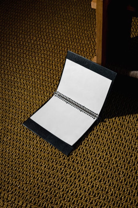 Open notebook mockup with blank pages on textured carpet background suitable for graphic design. Ideal for showcasing sketches branding templates.