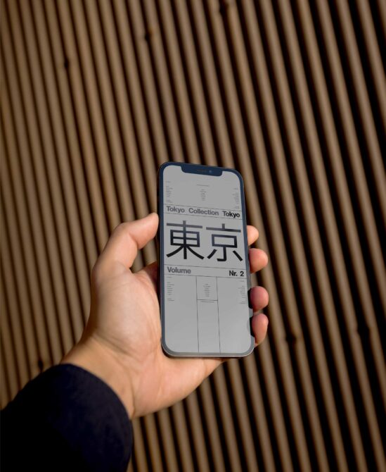 Hand holding blue phone displaying Tokyo Collection design with kanji