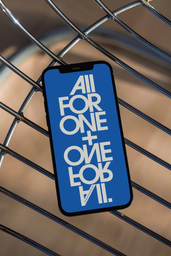 iPhone on metal grate background showing blue screen with bold white geometric type layout