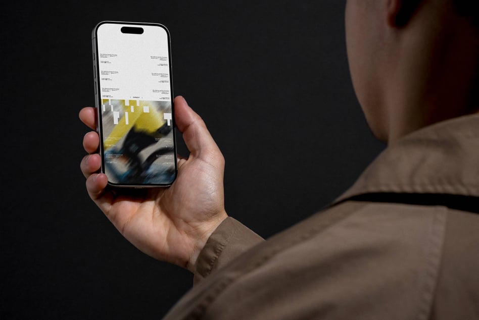Person holding iPhone displaying website layout with yellow accent colors against dark